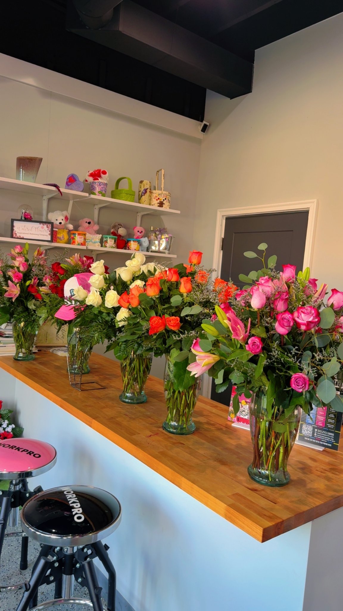 The Blossoms & Gems shop counter lined with fresh rose vase arrangements